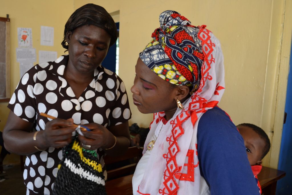 Odile Sannou, Workshopleiterin aus Benin, erklärt Baraka Oukpedjou aus Sokodé, wie sie den Henkel häkeln soll - Plastikmüll