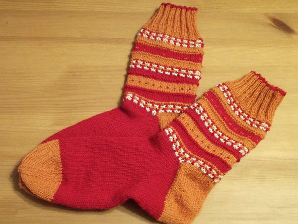 Iris ist auf Instagram unter Wollmaedchen zu finden. Sie hat ihre Anesasocks in Rot, Orange mit Weiß gestrickt.