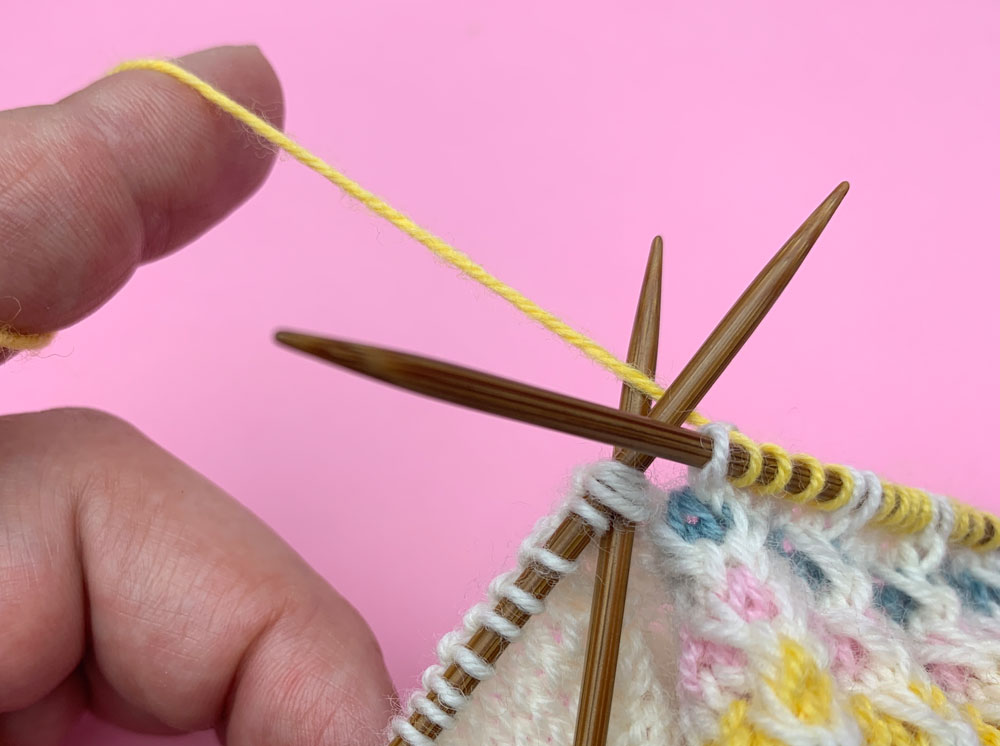 Nachdem die Oberfußmaschen gestrickt sind, wird die letzte Dreiermasche auf der Fersennadel rechts zusammengestrickt.