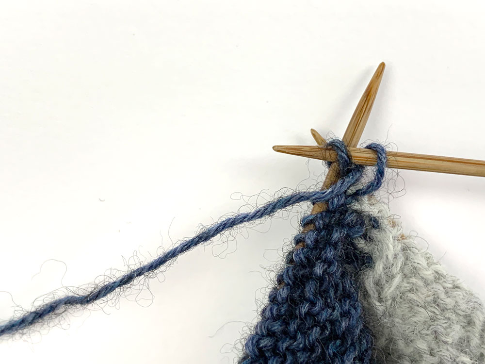 Die Rückreihe beginnt mit einem Umschlag. Die folgenden Maschen werden links gestrickt.