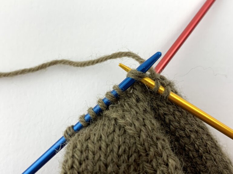 Zwei Maschen werden am Anfang des Bandes rechts zusammengestrickt.
