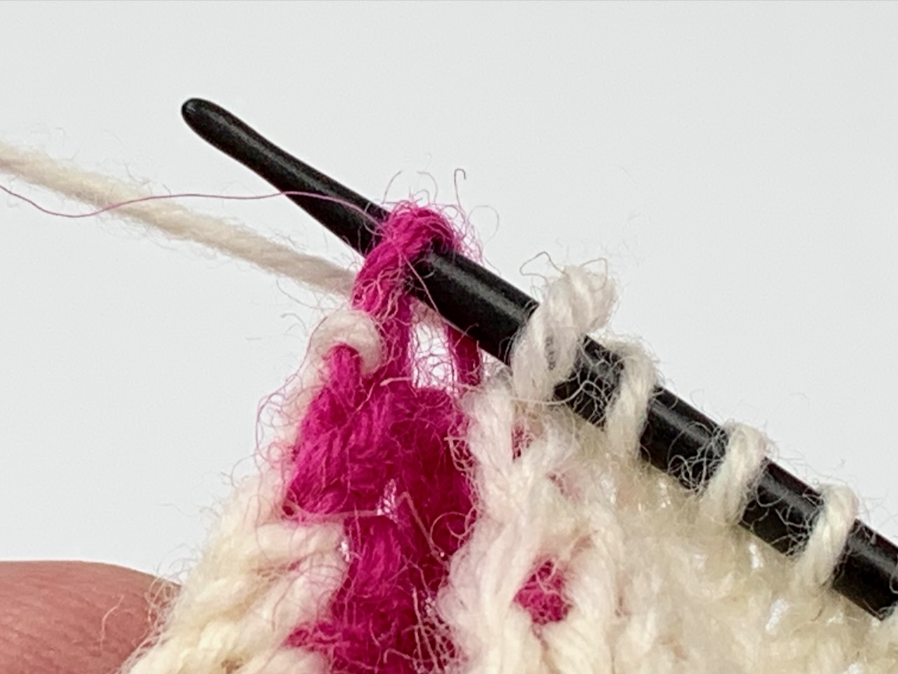 Socken stricken mit zwei Nadeln: Auf der Vorderseite werden die Knötchen der Rückseite mit den Randmaschen zusammengestrickt.
