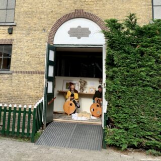 Die Holztüren der ehemaligen reformierten Kirche in Oosterend - geöffnet und darin zwei Personen am Spinnrad.